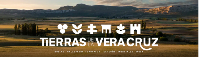 Paisaje rural del Noroeste de Murcia con el logotipo de Tierras de la Vera Cruz y nombres de los seis municipios.